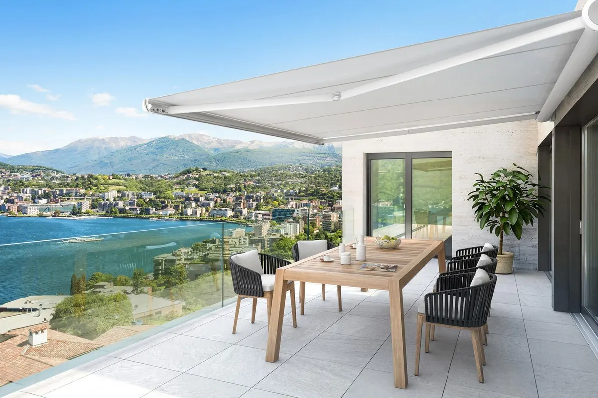 Store banne à coffre déployé au-dessus d'une terrasse avec table et chaises, vue dégagée sur l'eau